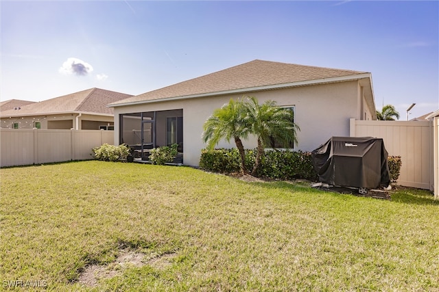 back of house with a fenced backyard, stucco siding, a yard, and a sunroom