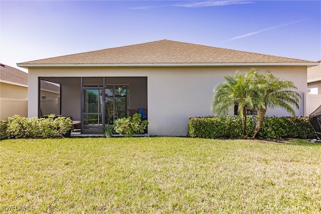 back of property featuring a lawn, a sunroom, and stucco siding