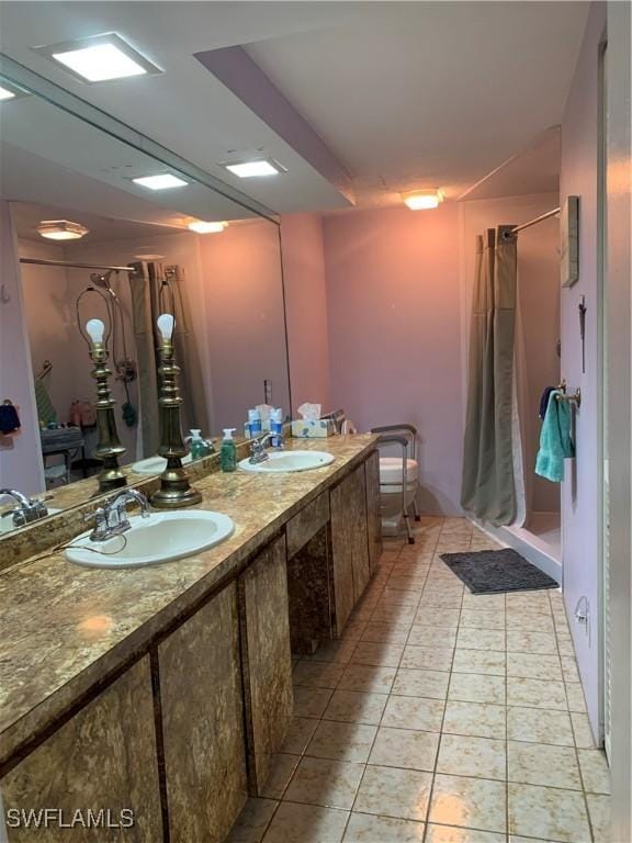bathroom with a stall shower, double vanity, a sink, and tile patterned floors