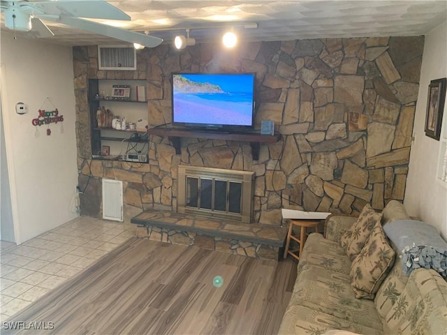 living room featuring visible vents, ceiling fan, wood finished floors, and a fireplace