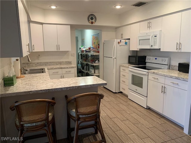 kitchen featuring visible vents, a sink, white appliances, light countertops, and wood tiled floor