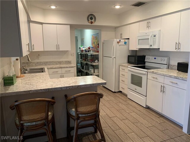 kitchen with light countertops, visible vents, a sink, and white appliances