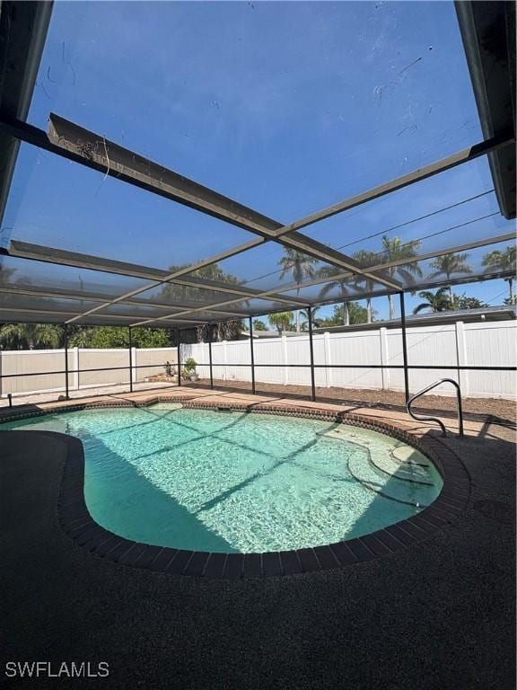 view of pool featuring glass enclosure, a fenced in pool, a fenced backyard, and a patio area