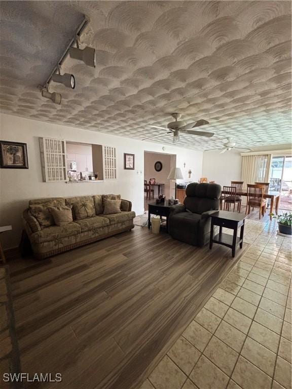living room featuring light tile patterned floors, a ceiling fan, track lighting, and a textured ceiling