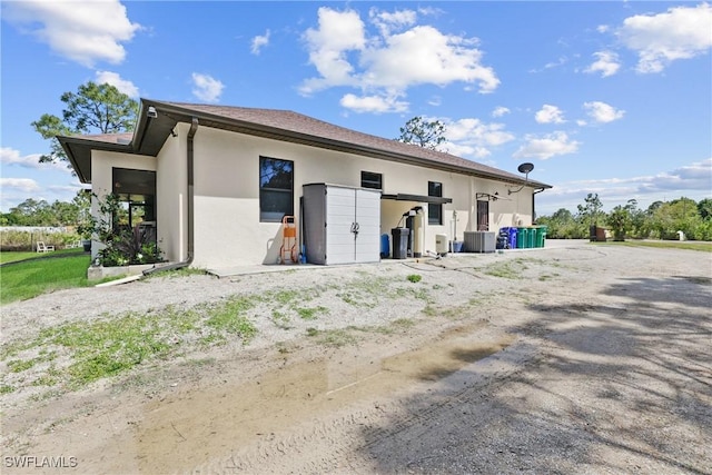 rear view of property with central AC and stucco siding