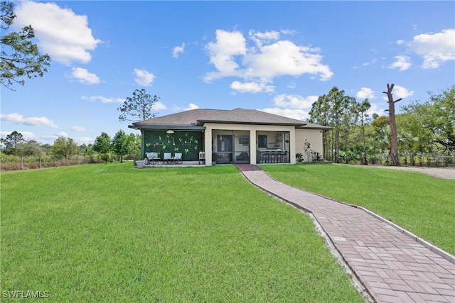 rear view of property with a lawn, a sunroom, and stucco siding