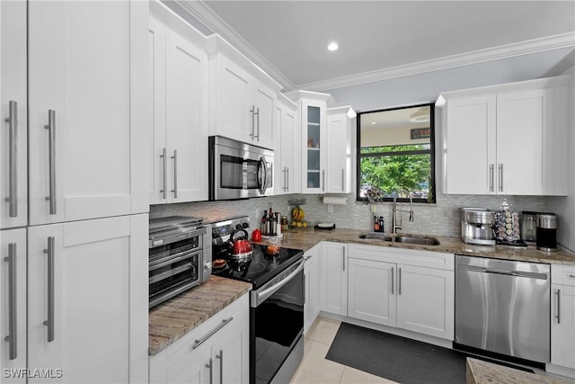 kitchen with a sink, light stone counters, tasteful backsplash, white cabinetry, and stainless steel appliances