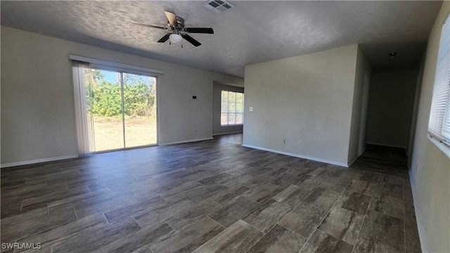 empty room with a textured ceiling, baseboards, visible vents, and ceiling fan