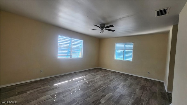 empty room with wood tiled floor, baseboards, visible vents, and ceiling fan