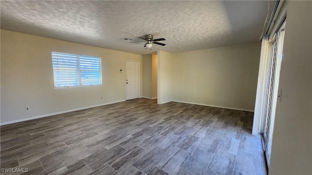 unfurnished room featuring visible vents, baseboards, ceiling fan, wood finished floors, and a textured ceiling