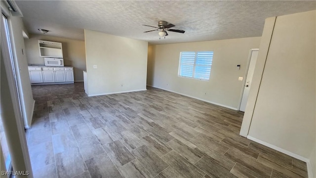 unfurnished living room with baseboards, a textured ceiling, a ceiling fan, and wood finished floors