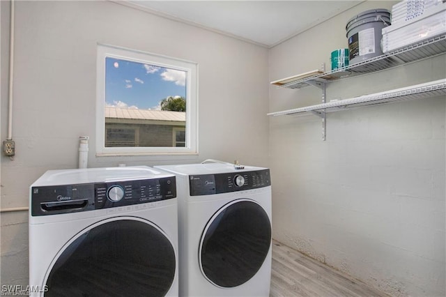 laundry area with concrete block wall, wood finished floors, laundry area, and washer and clothes dryer