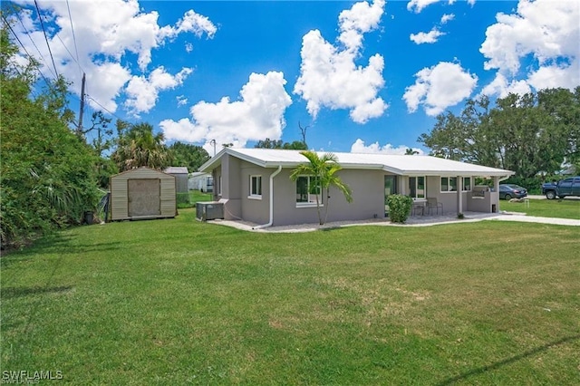 back of property featuring a storage unit, an outbuilding, a yard, and stucco siding