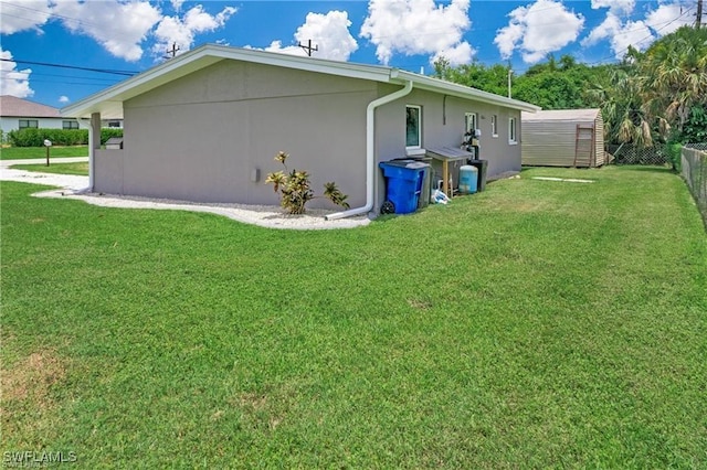 view of home's exterior featuring an outbuilding, stucco siding, a lawn, and fence