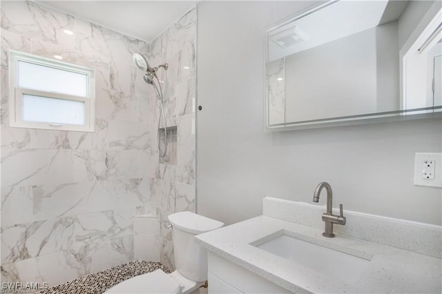 bathroom featuring vanity, toilet, and a tile shower