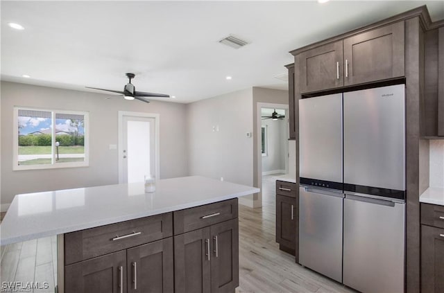 kitchen featuring light wood finished floors, dark brown cabinetry, freestanding refrigerator, and ceiling fan