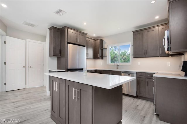 kitchen featuring dark brown cabinets, visible vents, light wood finished floors, and stainless steel appliances