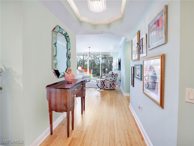 455 Cove Tower Dr Unit 303, Naples, FL 34110 - corridor with a chandelier, light wood-type flooring, ornamental molding, and a raised ceiling