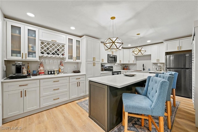 kitchen with white cabinets, light wood-type flooring, appliances with stainless steel finishes, and a sink