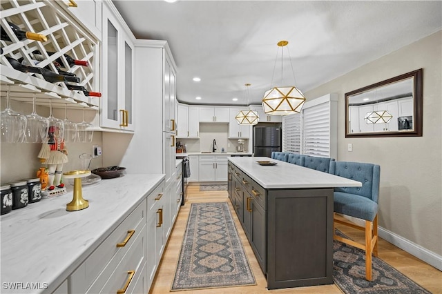 kitchen featuring white cabinets, black refrigerator, light wood finished floors, and a sink