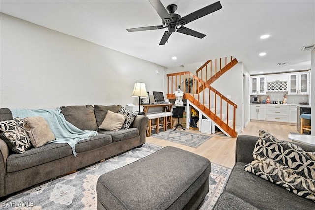 living room with stairway, a ceiling fan, recessed lighting, a bar, and light wood-type flooring