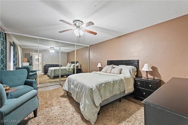 bedroom featuring ceiling fan, a textured ceiling, wood finished floors, and a textured wall