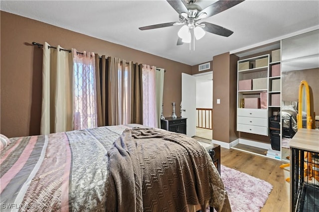 bedroom featuring visible vents, a ceiling fan, baseboards, and wood finished floors
