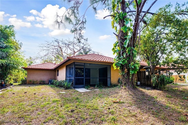 26955 Croise Dr, Bonita Springs, FL 34135 - rear view of property with a sunroom, stucco siding, a tile roof, and a lawn