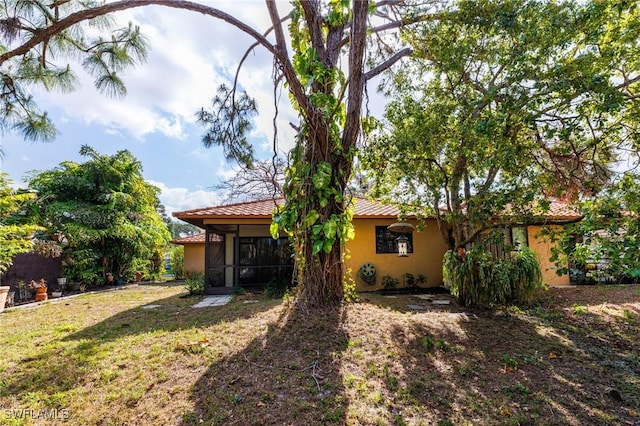 26955 Croise Dr, Bonita Springs, FL 34135 - back of property featuring a sunroom, a tiled roof, stucco siding, and a lawn