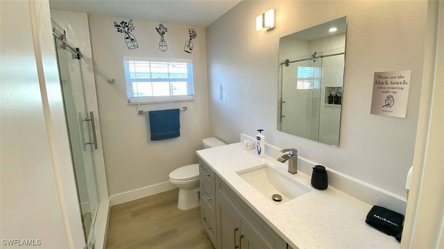 full bathroom featuring toilet, a stall shower, wood finished floors, baseboards, and vanity