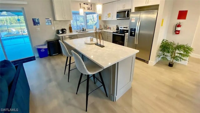 kitchen featuring appliances with stainless steel finishes, a breakfast bar area, light countertops, and a sink