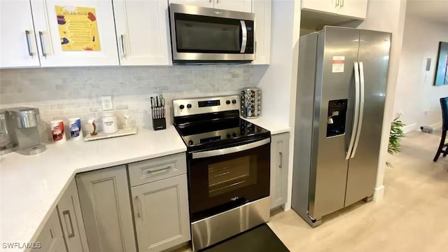 kitchen with white cabinetry, backsplash, appliances with stainless steel finishes, and light countertops