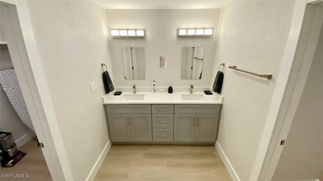 bathroom featuring double vanity, baseboards, and a sink