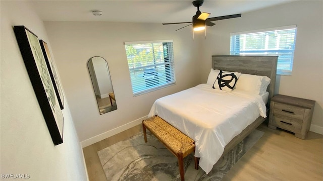 bedroom featuring baseboards, light wood-style floors, and ceiling fan