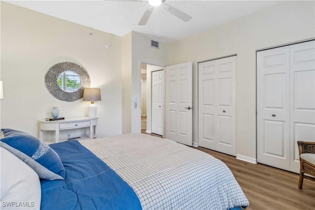 bedroom featuring wood finished floors, two closets, baseboards, and ceiling fan