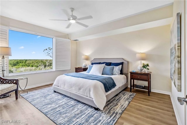 bedroom featuring baseboards, wood finished floors, and a ceiling fan