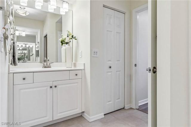 bathroom featuring baseboards, a closet, vanity, and tile patterned floors