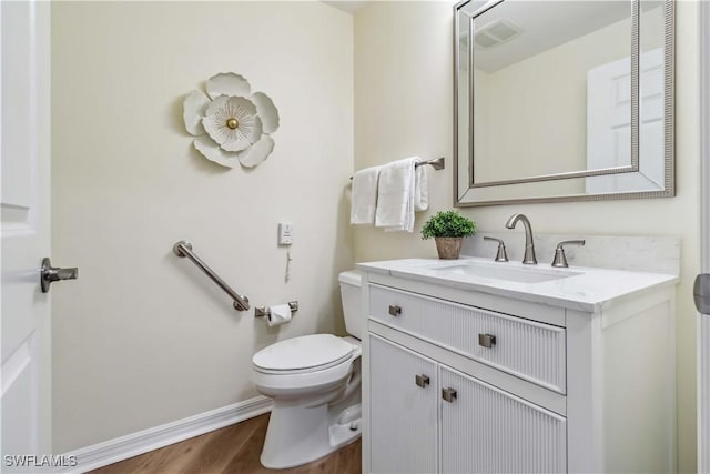 bathroom featuring wood finished floors, toilet, vanity, and baseboards