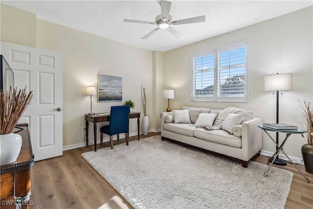 living area featuring wood finished floors, a ceiling fan, and baseboards