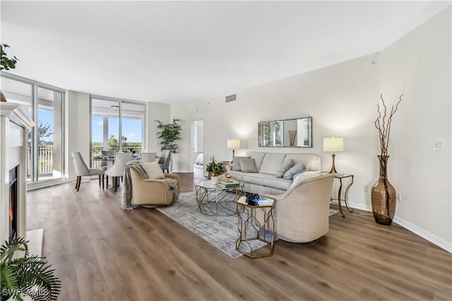 living room with wood finished floors, a lit fireplace, and baseboards