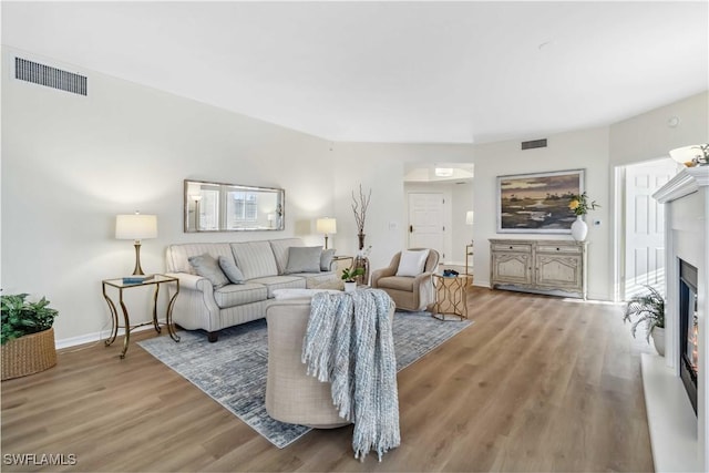 living room featuring wood finished floors, baseboards, and a glass covered fireplace