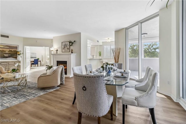 dining room with wood finished floors and a glass covered fireplace