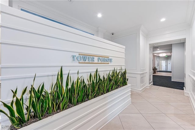 hallway featuring light tile patterned flooring, crown molding, a decorative wall, and recessed lighting