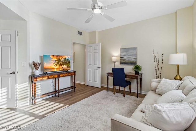 living area with an office area, ceiling fan, wood finished floors, and baseboards
