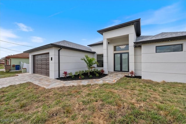 view of front facade with stucco siding, driveway, an attached garage, and a front yard