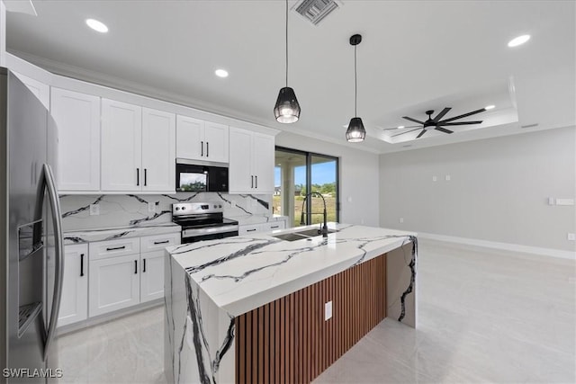 kitchen with a ceiling fan, a tray ceiling, a sink, stainless steel appliances, and backsplash