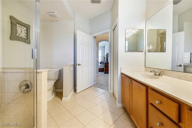 bathroom featuring tile patterned flooring, toilet, vanity, a tile shower, and baseboards