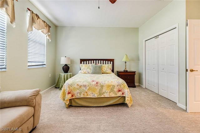 bedroom with light colored carpet, a closet, and baseboards