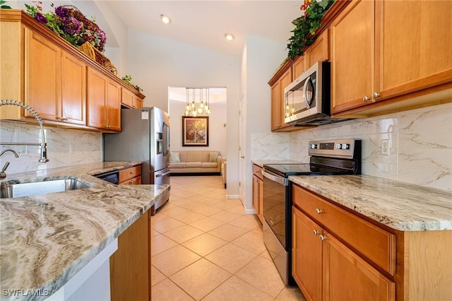 kitchen with stainless steel appliances, a sink, light tile patterned flooring, light stone countertops, and recessed lighting