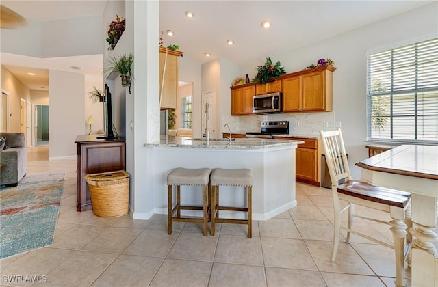 kitchen featuring appliances with stainless steel finishes, backsplash, light tile patterned floors, brown cabinetry, and recessed lighting